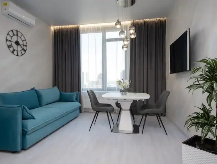 Квартира подобово у Києві — сучасна вітальня з блакитним диваном та панорамним вікном
